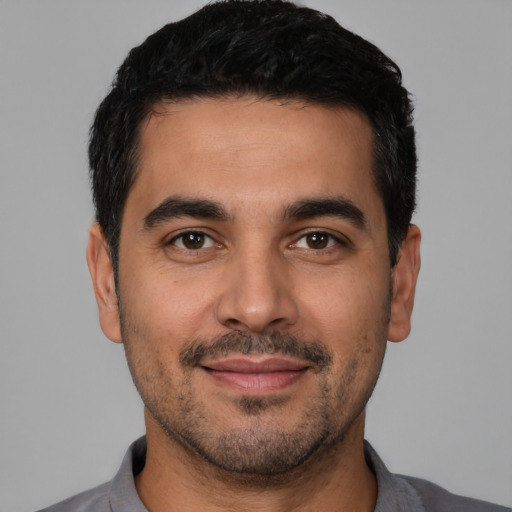 Joyful latino young-adult male with short  black hair and brown eyes