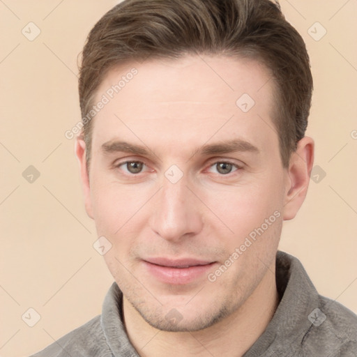 Joyful white young-adult male with short  brown hair and grey eyes