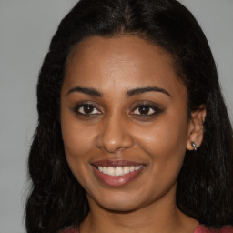 Joyful black young-adult female with long  brown hair and brown eyes