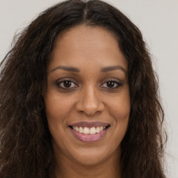 Joyful black young-adult female with long  brown hair and brown eyes