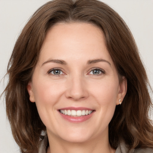 Joyful white adult female with medium  brown hair and grey eyes