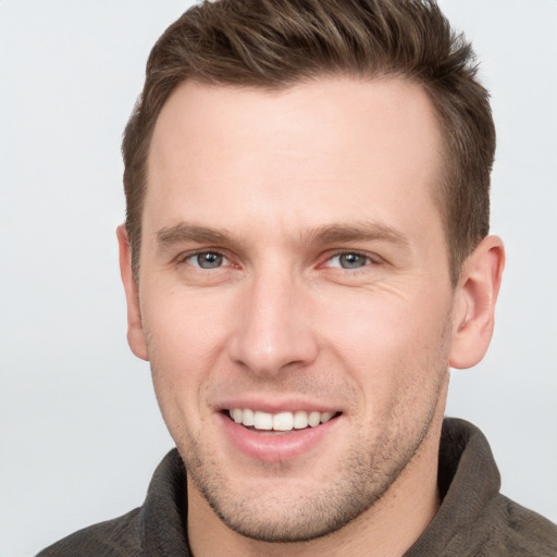 Joyful white young-adult male with short  brown hair and grey eyes