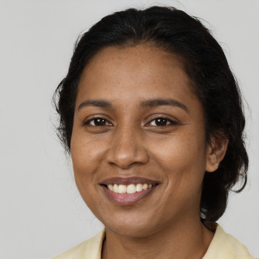 Joyful black young-adult female with long  brown hair and brown eyes