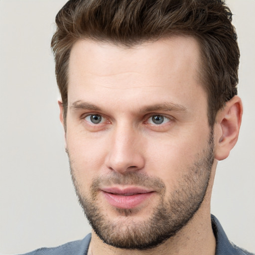 Joyful white young-adult male with short  brown hair and grey eyes