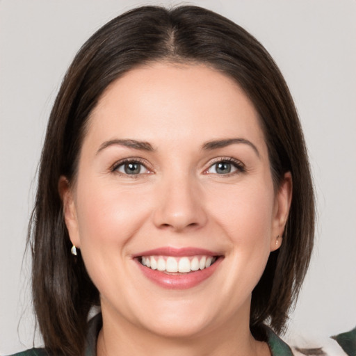 Joyful white young-adult female with medium  brown hair and grey eyes