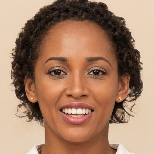 Joyful black young-adult female with long  brown hair and brown eyes