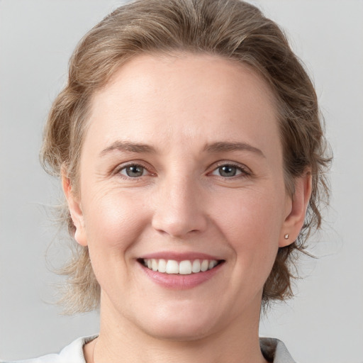 Joyful white young-adult female with medium  brown hair and grey eyes