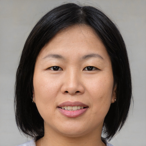 Joyful asian adult female with medium  brown hair and brown eyes