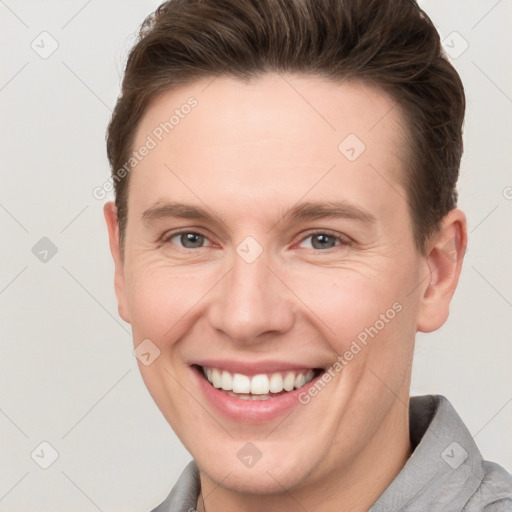 Joyful white young-adult male with short  brown hair and grey eyes