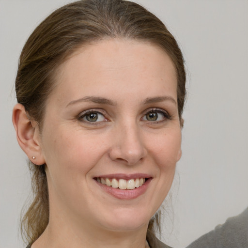 Joyful white young-adult female with medium  brown hair and grey eyes