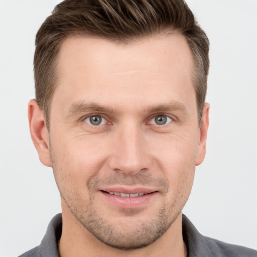 Joyful white young-adult male with short  brown hair and grey eyes