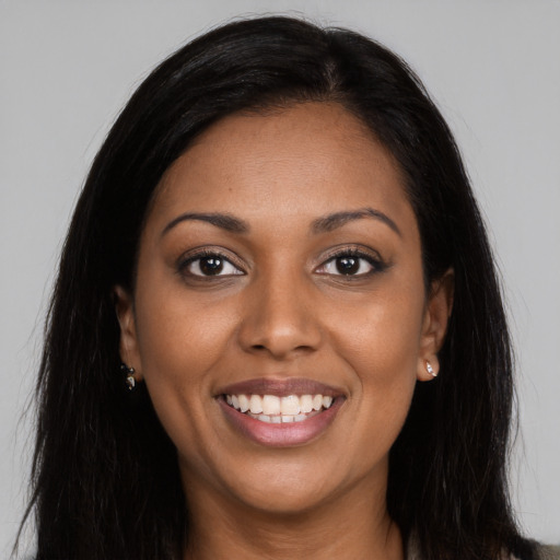 Joyful black young-adult female with long  brown hair and brown eyes