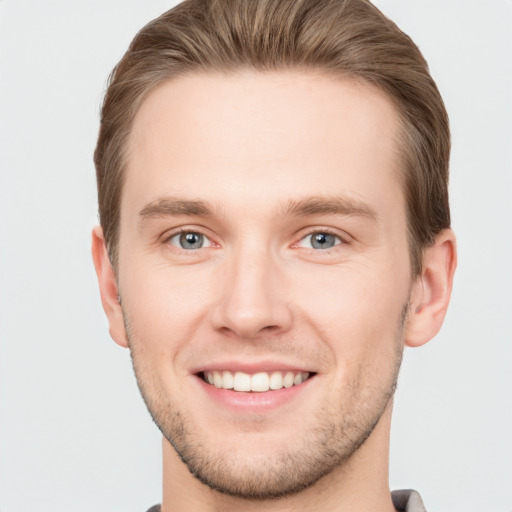 Joyful white young-adult male with short  brown hair and grey eyes