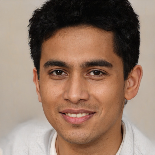 Joyful latino young-adult male with short  brown hair and brown eyes