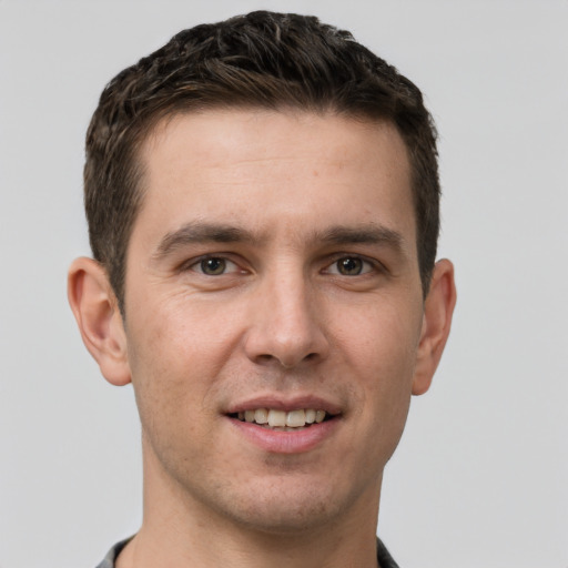 Joyful white young-adult male with short  brown hair and grey eyes