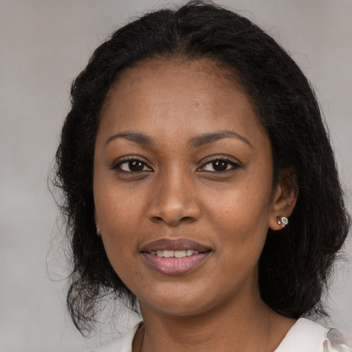 Joyful black young-adult female with long  brown hair and brown eyes