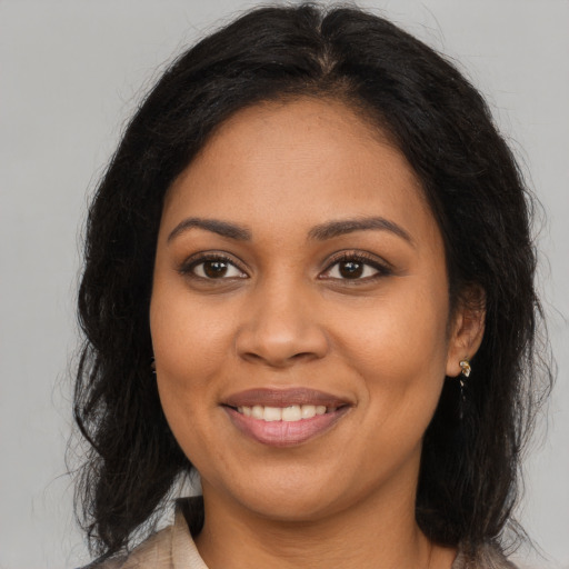 Joyful black young-adult female with long  brown hair and brown eyes