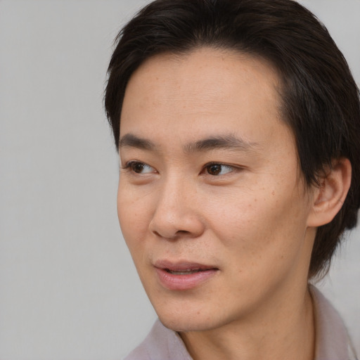 Joyful asian young-adult male with short  brown hair and brown eyes