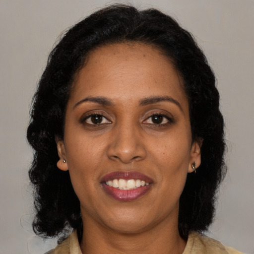 Joyful black young-adult female with long  black hair and brown eyes