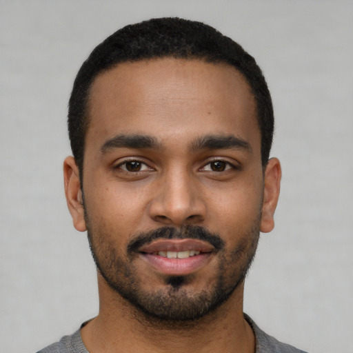 Joyful black young-adult male with short  black hair and brown eyes