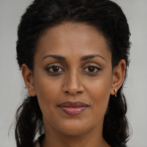 Joyful black young-adult female with long  brown hair and brown eyes