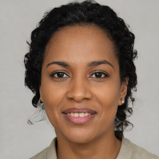 Joyful black young-adult female with long  brown hair and brown eyes