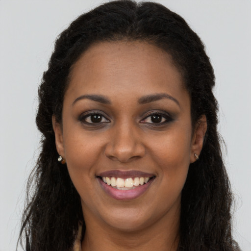 Joyful black young-adult female with long  brown hair and brown eyes