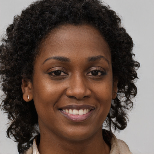 Joyful black young-adult female with long  brown hair and brown eyes