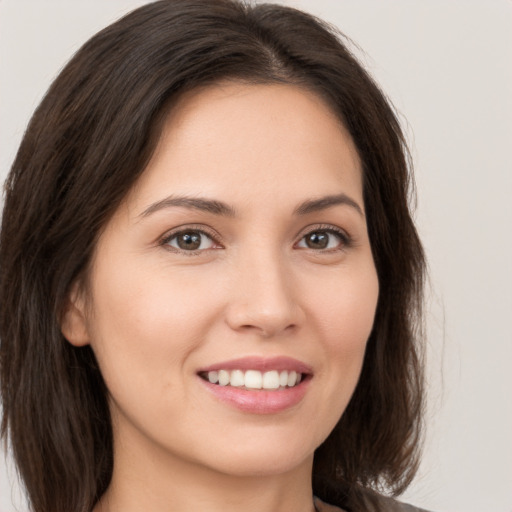 Joyful white young-adult female with long  brown hair and brown eyes