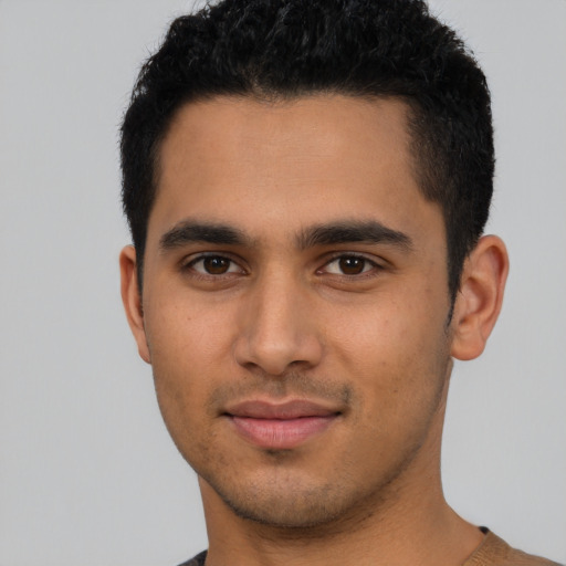 Joyful latino young-adult male with short  black hair and brown eyes
