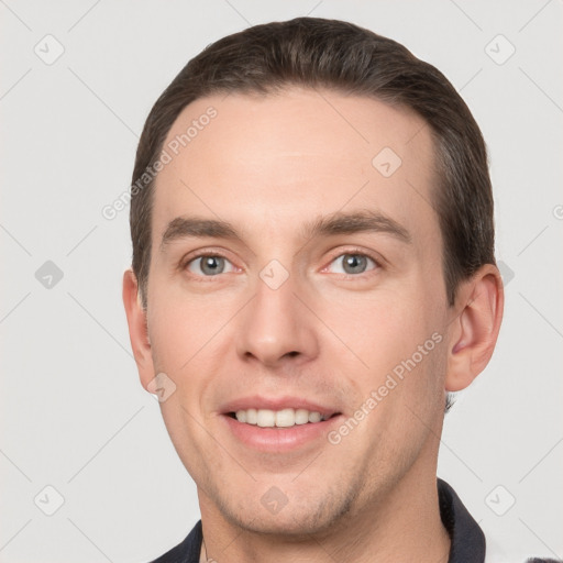 Joyful white young-adult male with short  brown hair and grey eyes