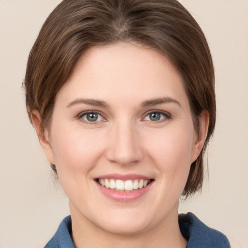 Joyful white young-adult female with medium  brown hair and grey eyes