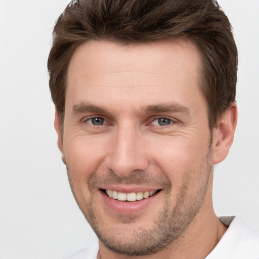 Joyful white young-adult male with short  brown hair and grey eyes