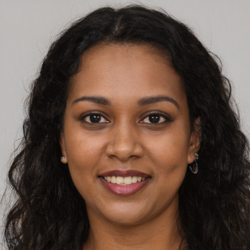 Joyful black young-adult female with long  brown hair and brown eyes