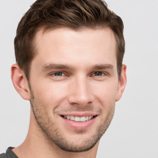 Joyful white young-adult male with short  brown hair and grey eyes