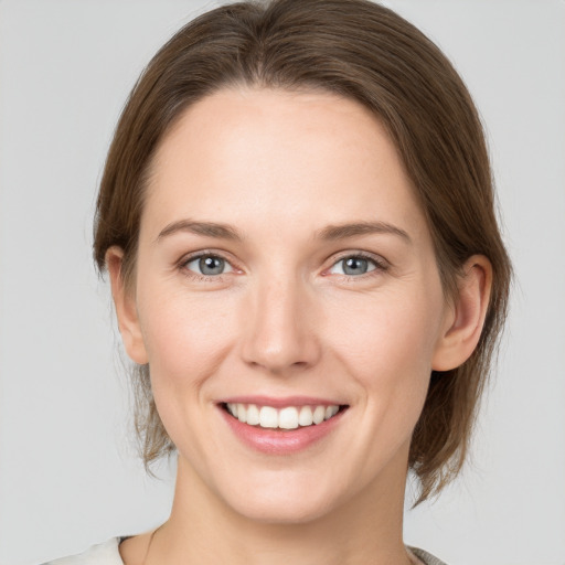 Joyful white young-adult female with medium  brown hair and grey eyes