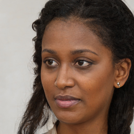 Joyful black young-adult female with long  brown hair and brown eyes