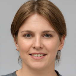 Joyful white young-adult female with medium  brown hair and grey eyes