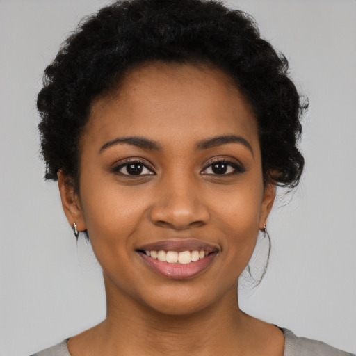 Joyful black young-adult female with short  black hair and brown eyes