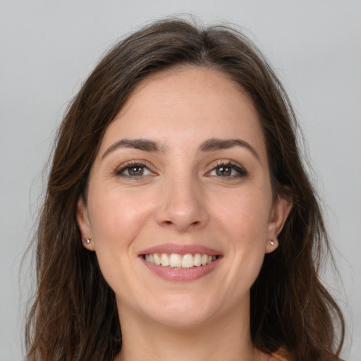 Joyful white young-adult female with long  brown hair and brown eyes