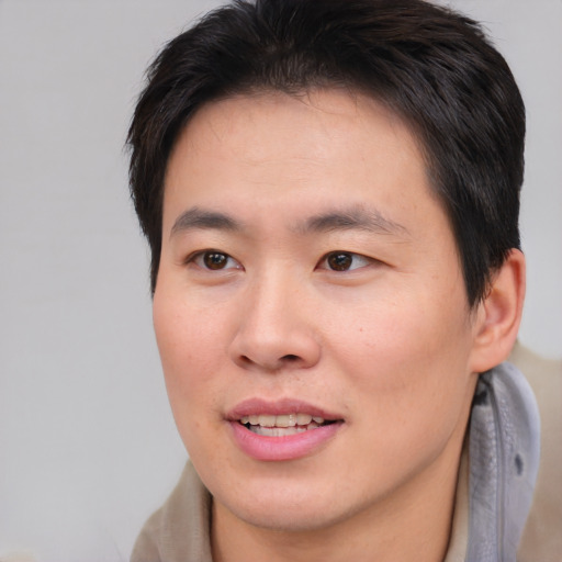 Joyful asian young-adult male with short  brown hair and brown eyes