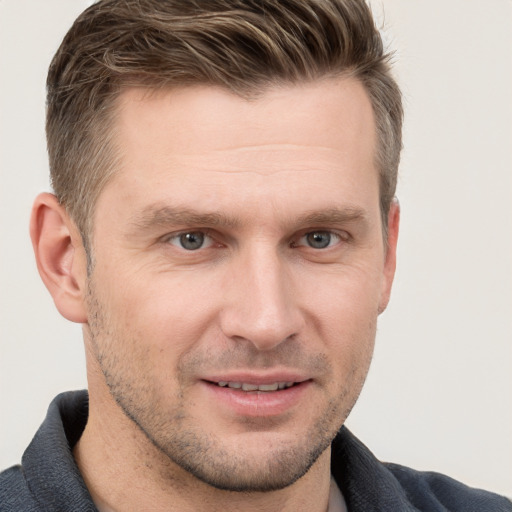 Joyful white young-adult male with short  brown hair and grey eyes