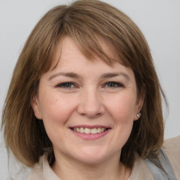 Joyful white young-adult female with medium  brown hair and grey eyes