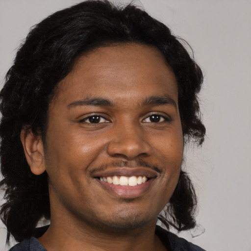 Joyful black young-adult male with medium  brown hair and brown eyes