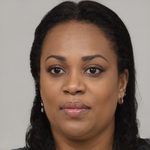 Joyful black young-adult female with long  black hair and brown eyes