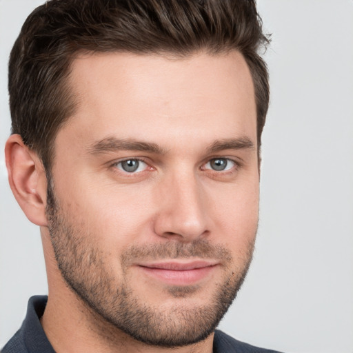 Joyful white young-adult male with short  brown hair and grey eyes