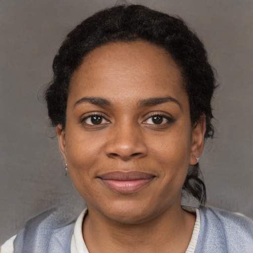 Joyful black young-adult female with short  black hair and brown eyes