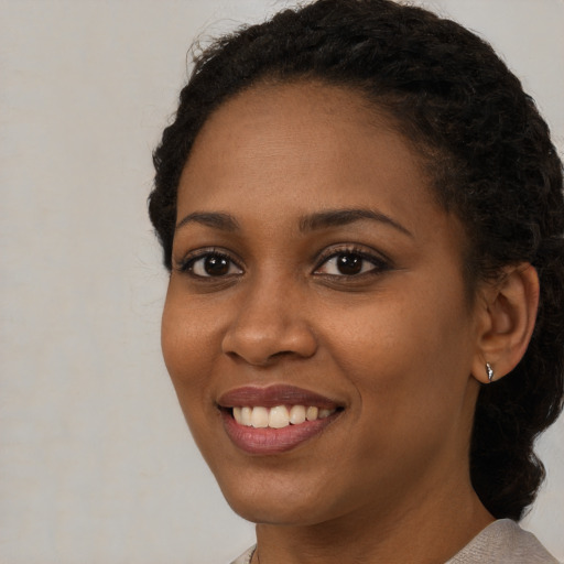 Joyful black young-adult female with medium  black hair and brown eyes