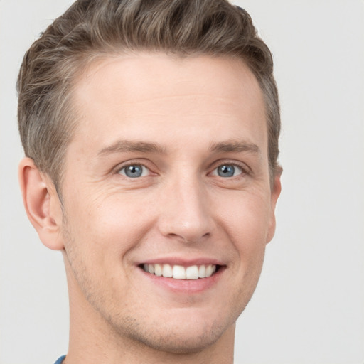 Joyful white young-adult male with short  brown hair and grey eyes