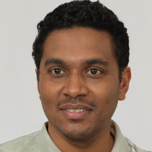 Joyful black young-adult male with short  black hair and brown eyes